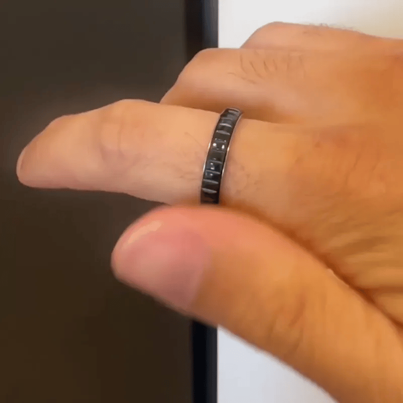 A close-up of a hand wearing a slim dark metallic spinning ring from Anxiety Rings Australia with a segmented, geometric design.
